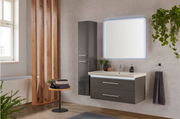 Moderne Badkombination mit beleuchtetem Spiegel, grauem Waschtisch und Hochschrank, seitliche Perspektive.