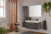 Moderne Badkombination mit beleuchtetem Spiegel, grauem Waschtisch und Hochschrank, seitliche Perspektive.