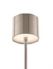 Nahaufnahme einer modernen Akku-Stehleuchte mit einem strukturierten, zylindrischen Lampenschirm in neutraler Farbe, von unten betrachtet.