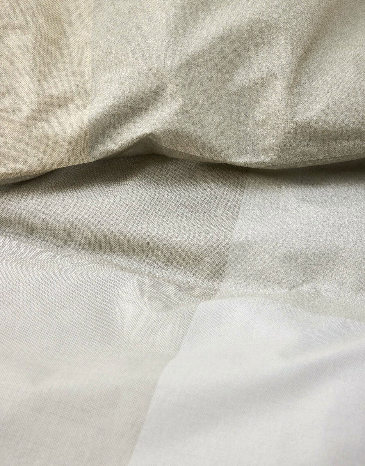 Nahaufnahme von beiger Bettwäsche mit feiner Textur, perspektivisch von oben fotografiert.