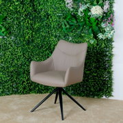Moderne fauteuil in beige met een zwart metalen frame, voor een groene plantenwand, zijaanzicht