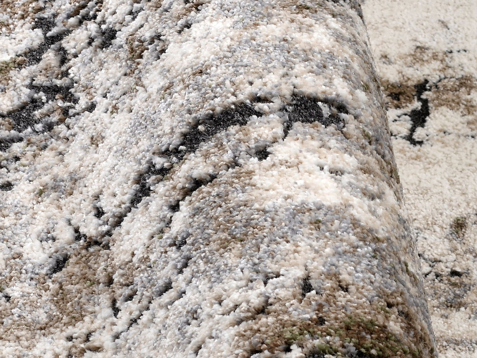 Nahaufnahme eines Designer-Teppichs mit abstraktem Muster in Beige-, Grau- und Schwarztönen, seitliche Perspektive