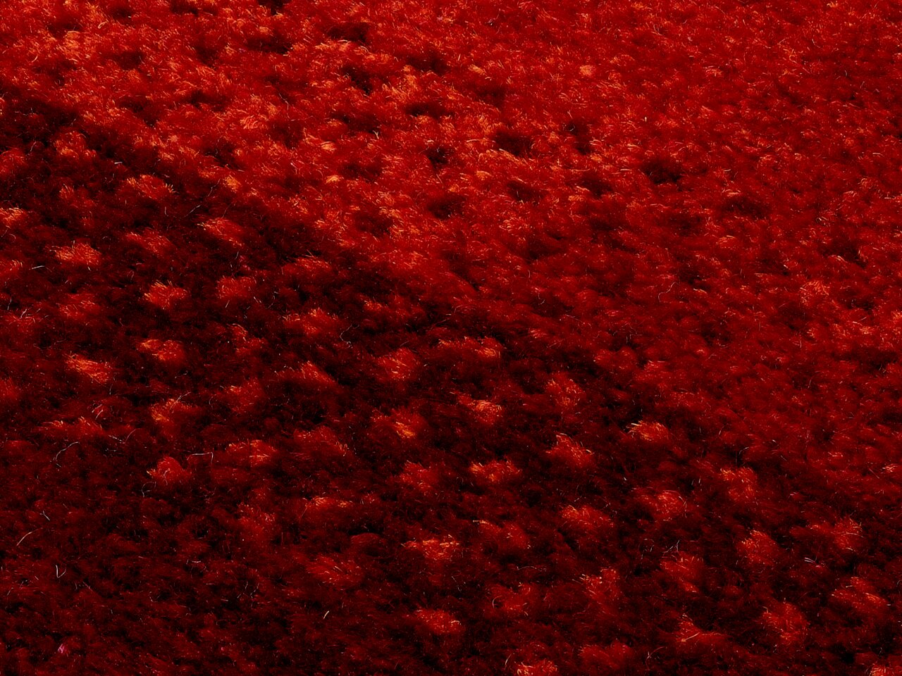 Nahaufnahme eines roten Wollteppichs mit strukturierter Oberfläche, diagonale Perspektive