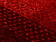 Nahaufnahme eines roten Wollteppichs mit strukturierter Oberfläche, diagonale Perspektive