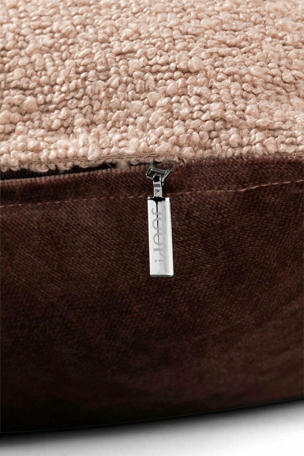 Nahaufnahme einer Zierkissenhülle mit beigem, strukturiertem Stoff und braunem Reißverschluss, seitliche Perspektive