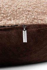 Nahaufnahme einer Zierkissenhülle mit beigem, strukturiertem Stoff und braunem Reißverschluss, seitliche Perspektive