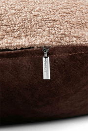 Nahaufnahme einer Zierkissenhülle mit beigem, strukturiertem Stoff und braunem Reißverschluss, seitliche Perspektive