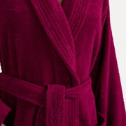 Nahaufnahme eines weinroten Bademantels mit Schalkragen und Gürtel, Vorderansicht