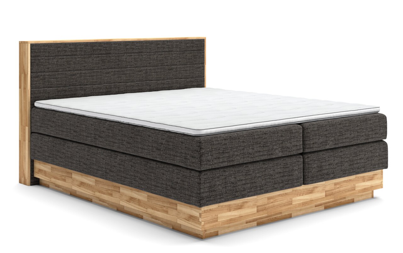 Boxspringbett mit grauem Stoffbezug und Holzrahmen, seitliche Perspektive