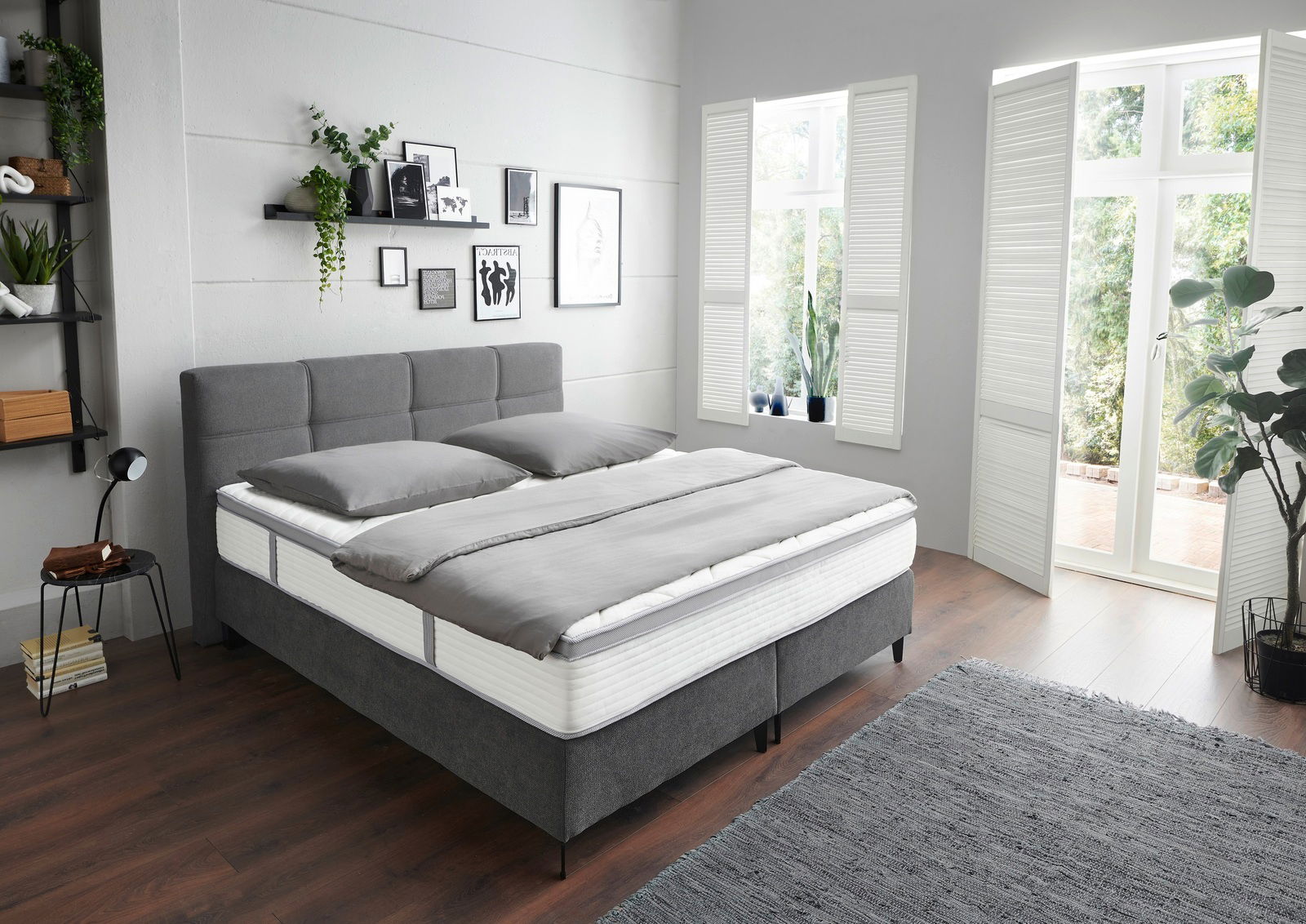 Modernes Boxspringbett in einem hellen Schlafzimmer, seitliche Perspektive