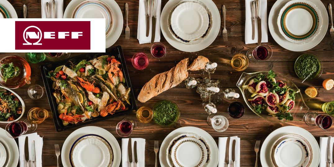 Ein wunderschön arrangierter Esstisch mit verschiedenen Gerichten, bunten Getränken und Besteck mit dem NEFF-Logo in der Ecke.