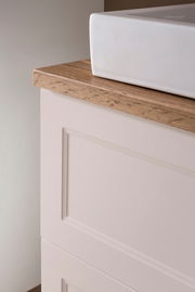 Nahaufnahme eines Waschtisch-Sets mit weißem Waschbecken und Holzarbeitsplatte, seitliche Perspektive.