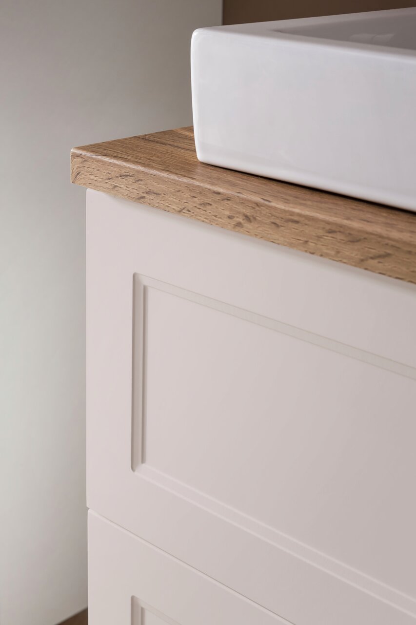 Nahaufnahme eines Waschtisch-Sets mit weißem Waschbecken und Holzarbeitsplatte, seitliche Perspektive.