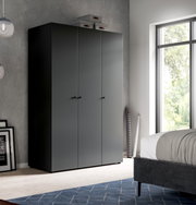 Schwarzer, minimalistischer Kleiderschrank mit drei Türen und kleinen Griffen im Schlafzimmer, frontale Ansicht mit leichter Perspektive von links.