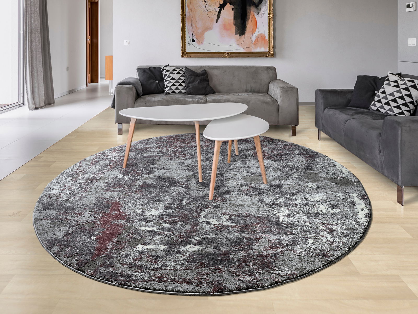 Runder Designer Teppich in einem modernen Wohnzimmer mit grauen Sofas und einem Couchtisch, aus der Vogelperspektive betrachtet.