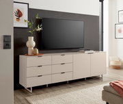 Modernes, hellbeiges TV-Lowboard mit Schubladen und Türen auf schlanken Metallfüßen, mit Fernseher und Deko im Wohnzimmer, frontale Perspektive.