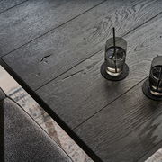 Nahaufnahme eines schwarzen Esstisches aus Holz mit zwei Gläsern Wasser, von oben fotografiert.