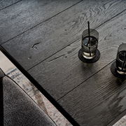 Nahaufnahme eines schwarzen Esstisches aus Holz mit zwei Gläsern Wasser, von oben fotografiert.