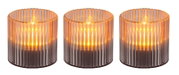 Drei zylindrische Solarleuchten mit geriffeltem Glasdesign, die warmes Licht ausstrahlen, aus der Frontalperspektive.