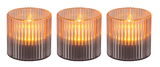 Drei zylindrische Solarleuchten mit geriffeltem Glasdesign, die warmes Licht ausstrahlen, aus der Frontalperspektive.