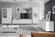 Moderne woonkamer met een wit dressoir en een ladekast, gezien van voren en van opzij, omringd door stijlvolle decoraties en een grote televisie.