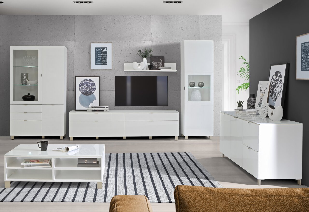 Moderne woonkamer met een wit dressoir en een ladekast, gezien van voren en van opzij, omringd door stijlvolle decoraties en een grote televisie.