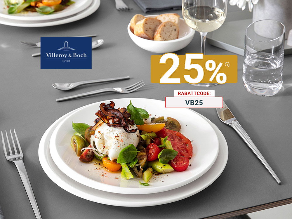 Modern gedeckter Esstisch mit weißem Villeroy & Boch Geschirr, Edelstahlbesteck, Weißweinglas und Burrata-Tomatensalat auf grauer Tischplatte.