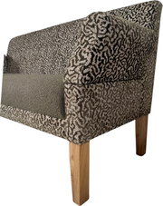 Gepolsterter Sessel mit gemustertem Stoffbezug in Grau/Schwarz, Sitzfläche in Uni-Grau und Holzbeinen, Detailansicht aus seitlicher Vorderansicht (3/4-Perspektive)
