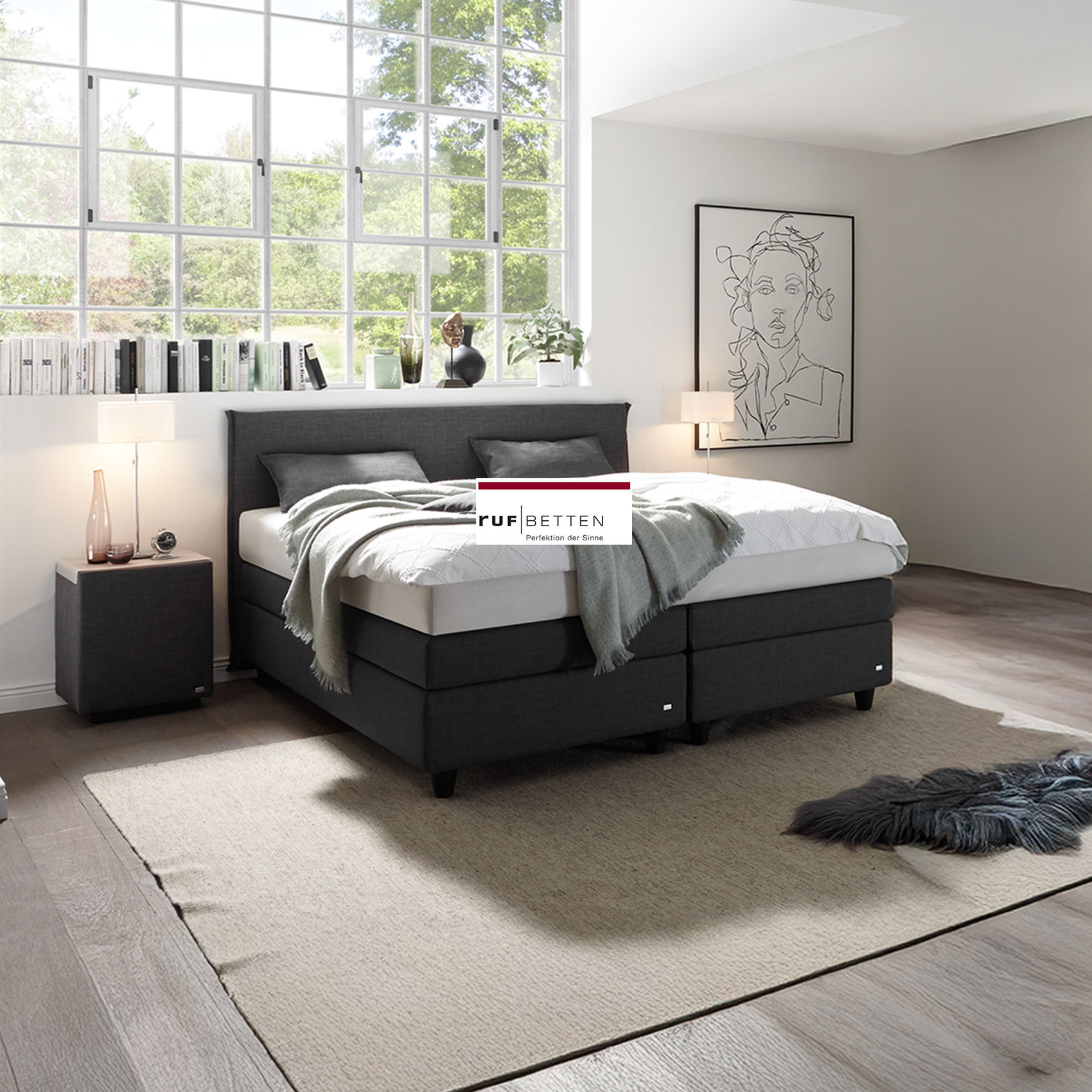 Modernes Boxspringbett in Grau in hellem Schlafzimmer mit großem Fenster