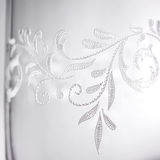 Nahaufnahme eines Bechers mit romantischem, floralen Muster in Weiß auf transparentem Hintergrund.