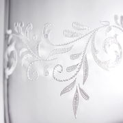 Nahaufnahme eines Bechers mit romantischem, floralen Muster in Weiß auf transparentem Hintergrund.