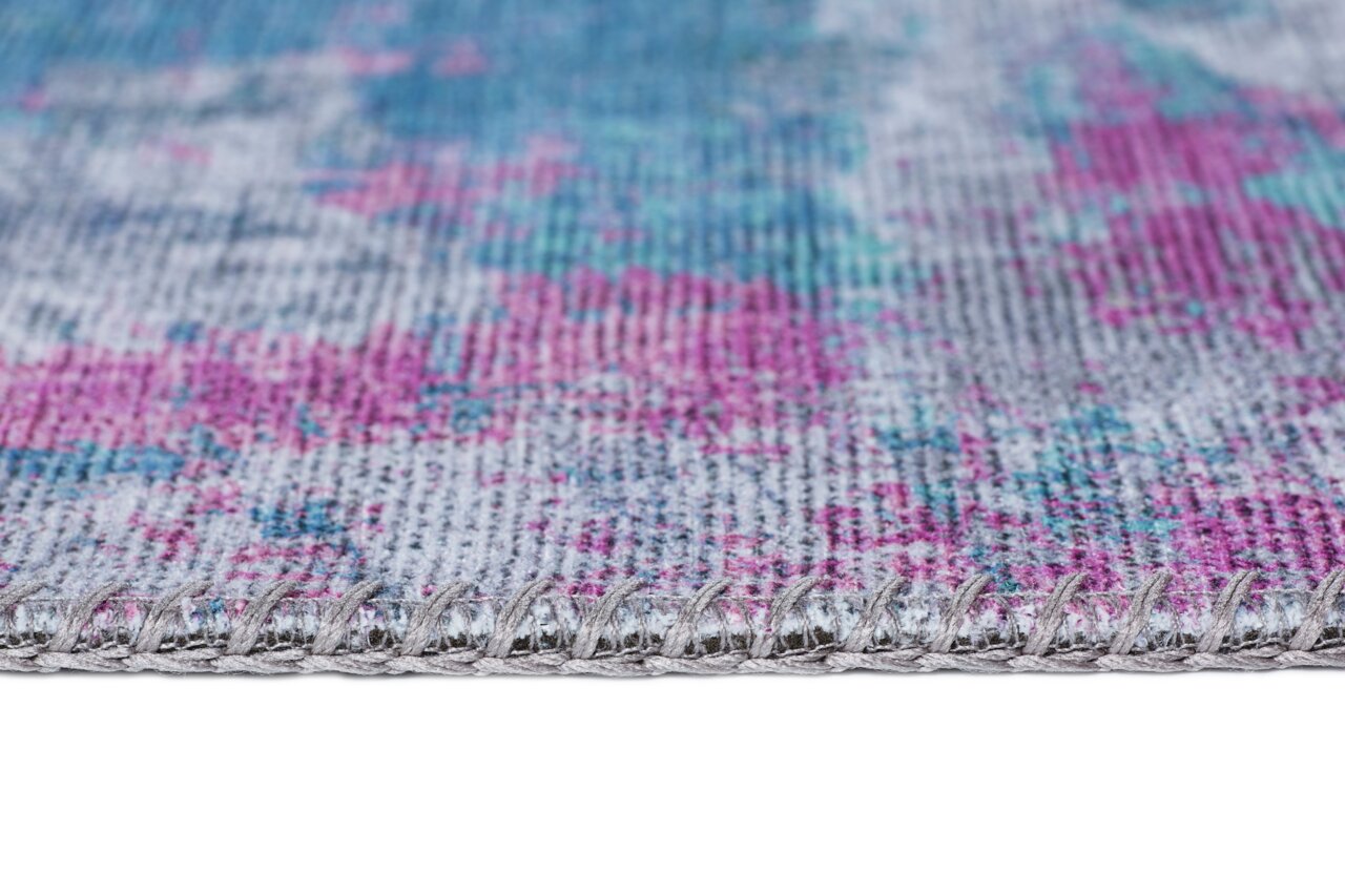 Nahaufnahme eines Teppichs mit buntem Muster in Blau- und Pinktönen, seitliche Perspektive.