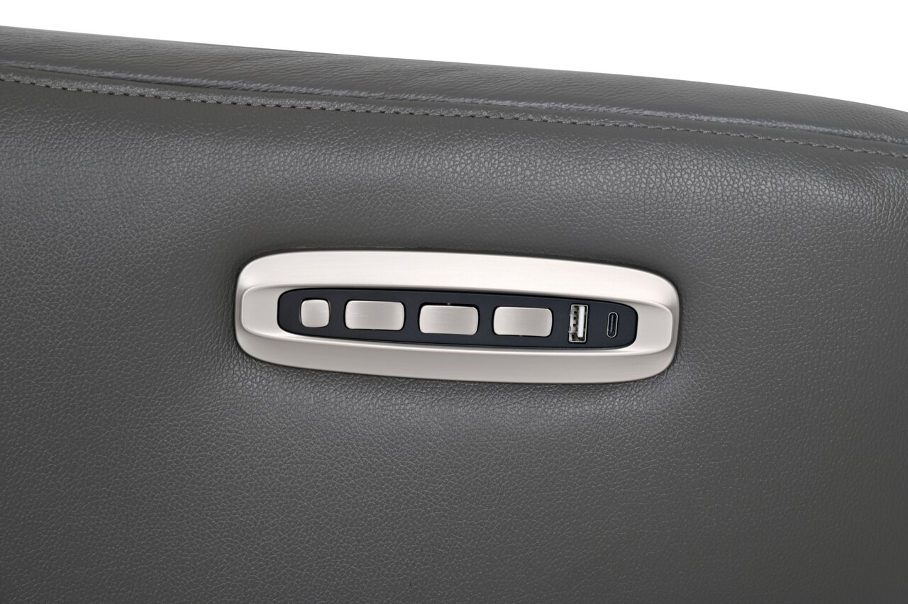 Close-up van de bedieningsknoppen van een grijze relaxfauteuil met USB-aansluiting en knoppen op de armleuning.