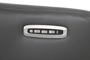 Close-up van de bedieningsknoppen van een grijze relaxfauteuil met USB-aansluiting en knoppen op de armleuning.