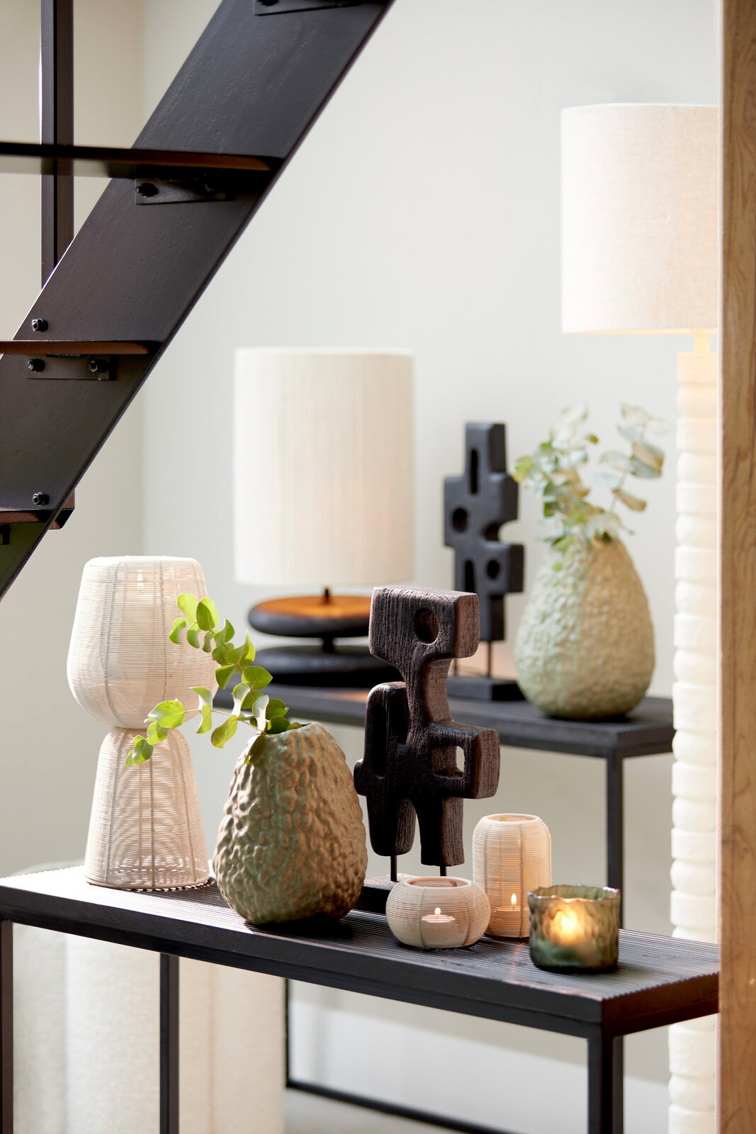 Teelicht in mattem Design auf einem Tisch, umgeben von dekorativen Vasen und Skulpturen, seitliche Perspektive