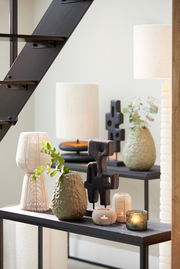 Teelicht in mattem Design auf einem Tisch, umgeben von dekorativen Vasen und Skulpturen, seitliche Perspektive