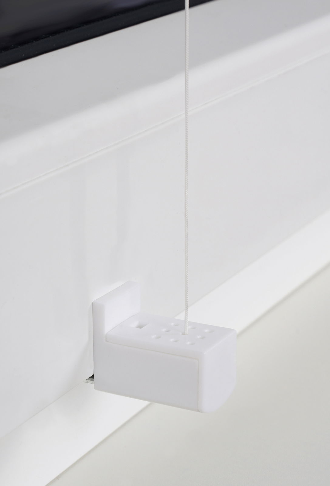 Nahaufnahme eines weißen Plissee-Bedienmechanismus mit Schnur, seitliche Perspektive