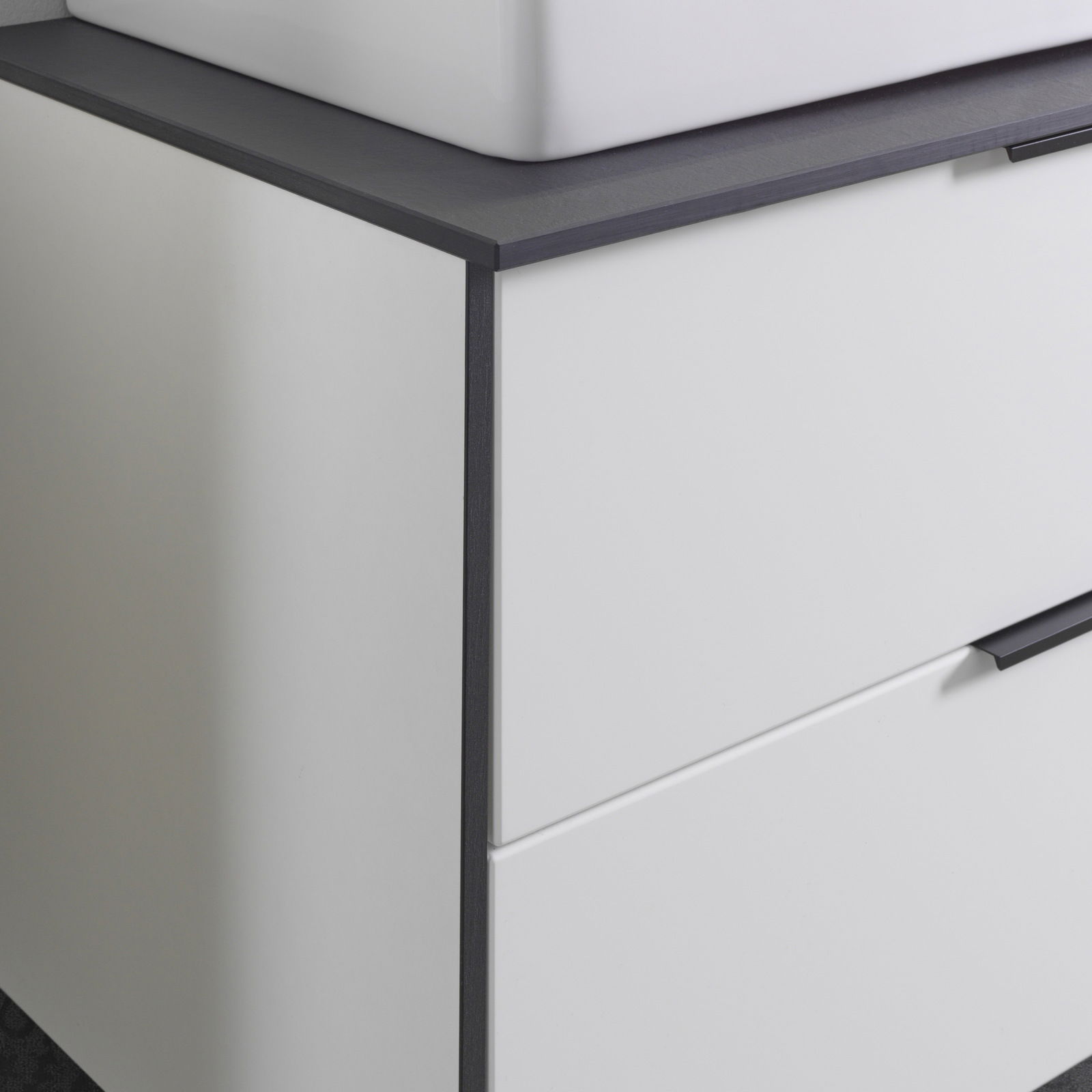 Nahaufnahme eines modernen Waschtisch-Sets mit weißem Schrank und dunkler Arbeitsplatte, seitliche Perspektive