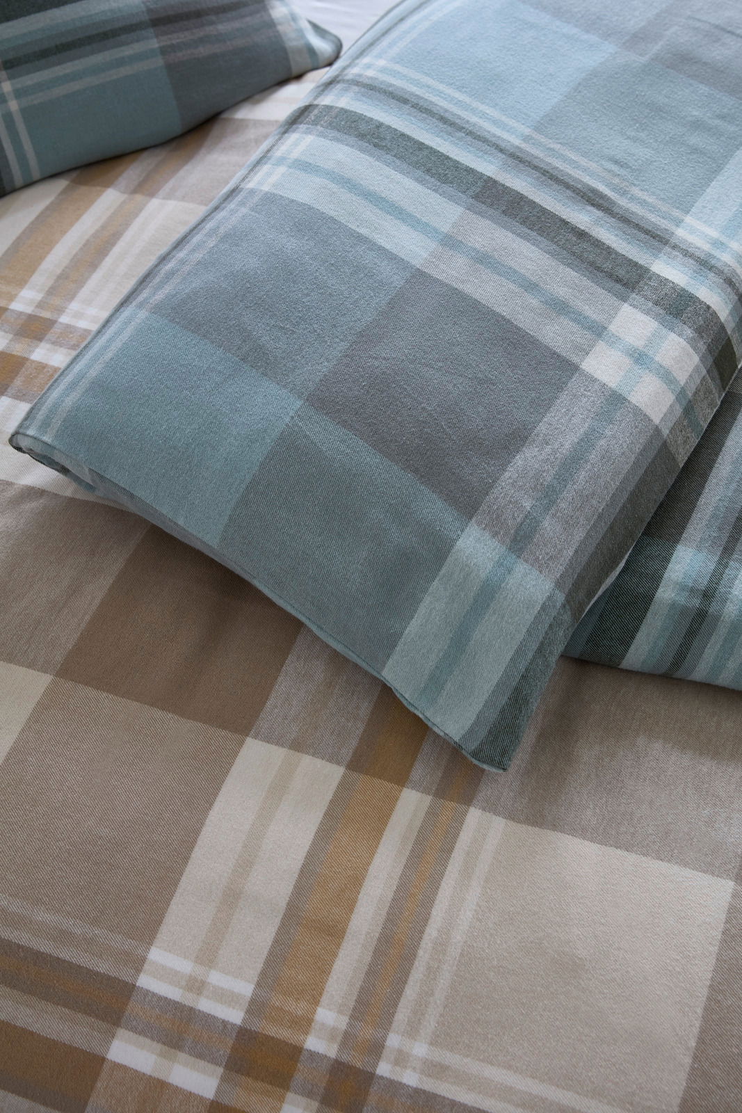Nahaufnahme von karierten Bettwäschesets in Blau- und Brauntönen, von oben betrachtet.