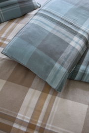 Nahaufnahme von karierten Bettwäschesets in Blau- und Brauntönen, von oben betrachtet.