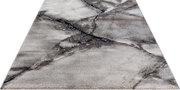 Moderner Teppich in Grau- und Beigetönen mit marmorierter Steinoptik und dunklen Adern, schräg von oben in Perspektive fotografiert