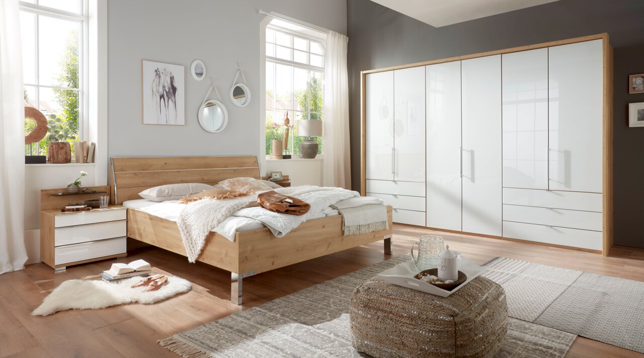 Schlafzimmeransicht mit Futonbett aus Holz, Nachtschrank-Set und großem Falttürenschrank, seitliche Perspektive.