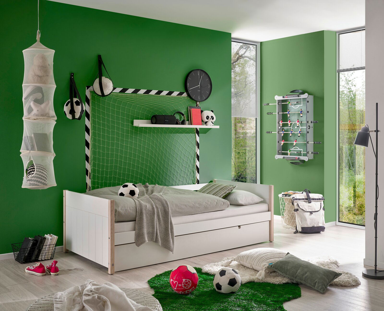 Jugendbett in einem sportlich dekorierten Zimmer mit Fußballthema, seitliche Perspektive