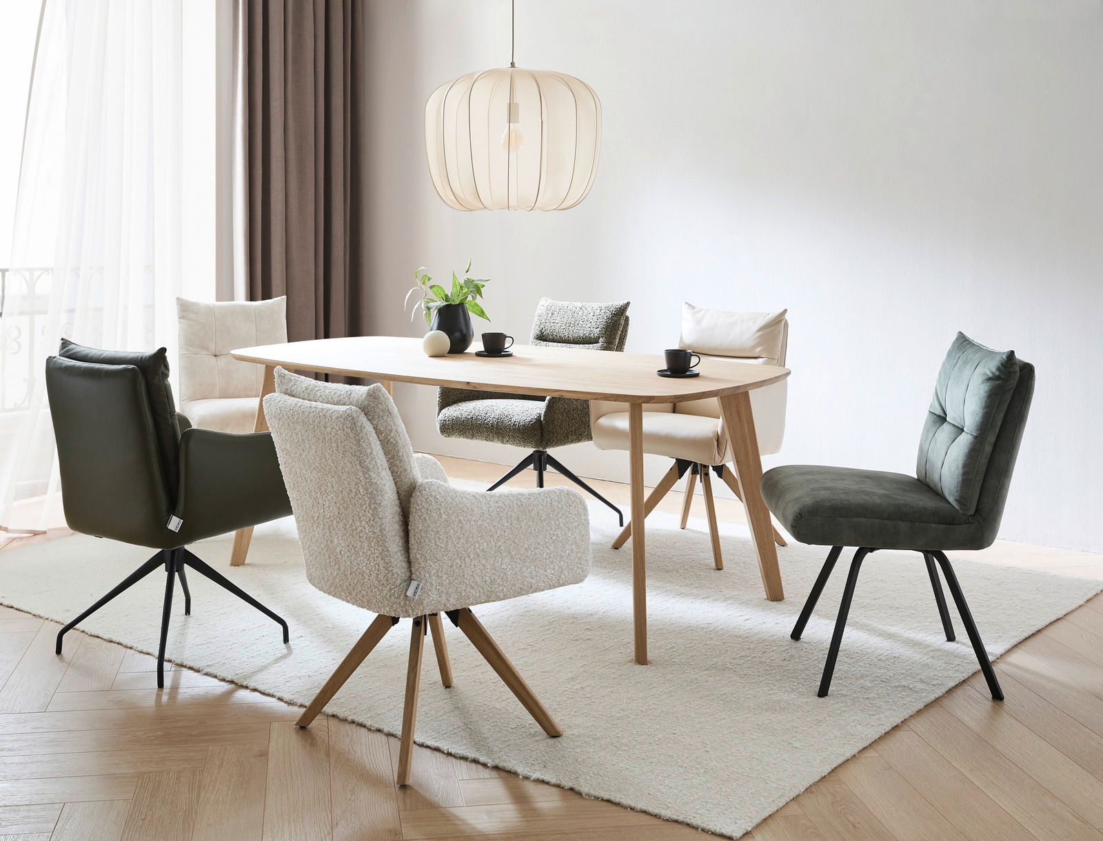 Moderner Esstisch mit verschiedenen Stühlen in einem hellen Raum, seitliche Perspektive