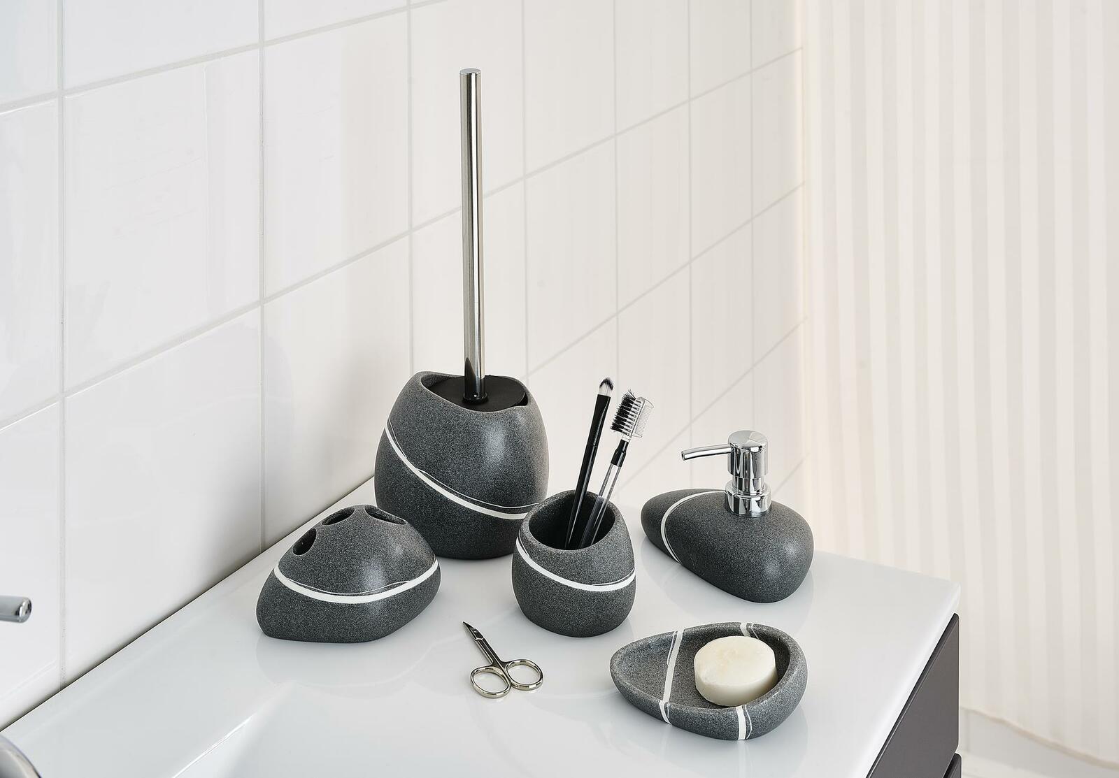 WC-Bürstengarnitur Little Rock in Steinoptik, bestehend aus WC-Bürste, Seifenspender, Zahnbürstenhalter und Seifenschale, auf einem weißen Waschbecken von schräg oben fotografiert.