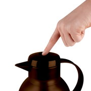 Close-up van een bruine thermoskan Samba QP 1,0 l met een vinger die op het deksel drukt.