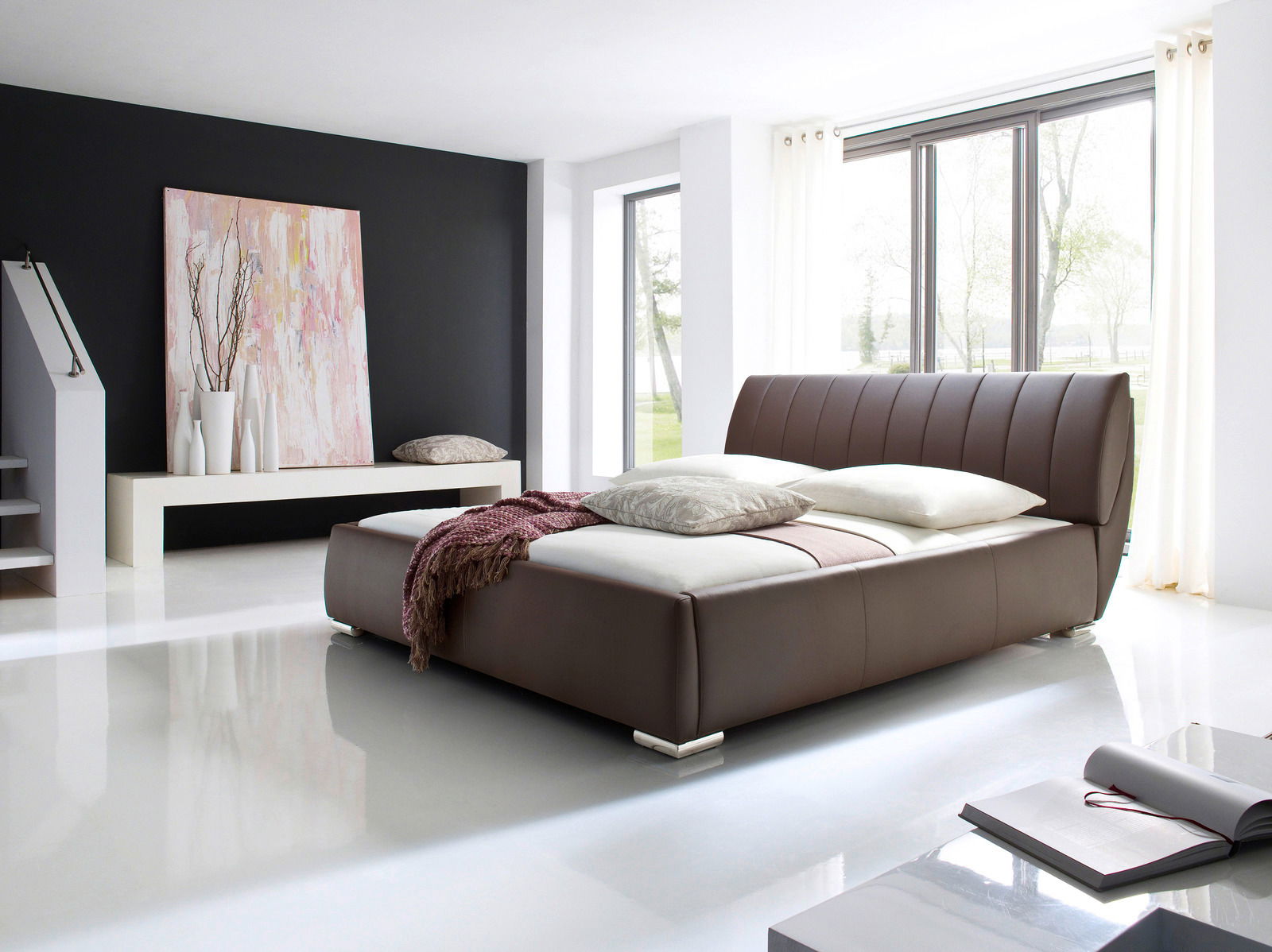 Modernes Polsterbett in einem hellen Raum mit großen Fenstern, seitliche Perspektive