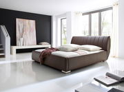 Modernes Polsterbett in einem hellen Raum mit großen Fenstern, seitliche Perspektive