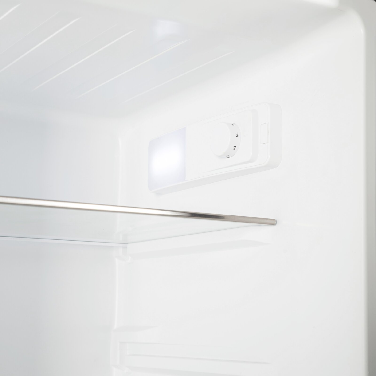 Innenansicht eines weißen Kühlschranks mit LED-Innenbeleuchtung und Temperaturregler-Drehknopf, schräg von vorne oben fotografiert