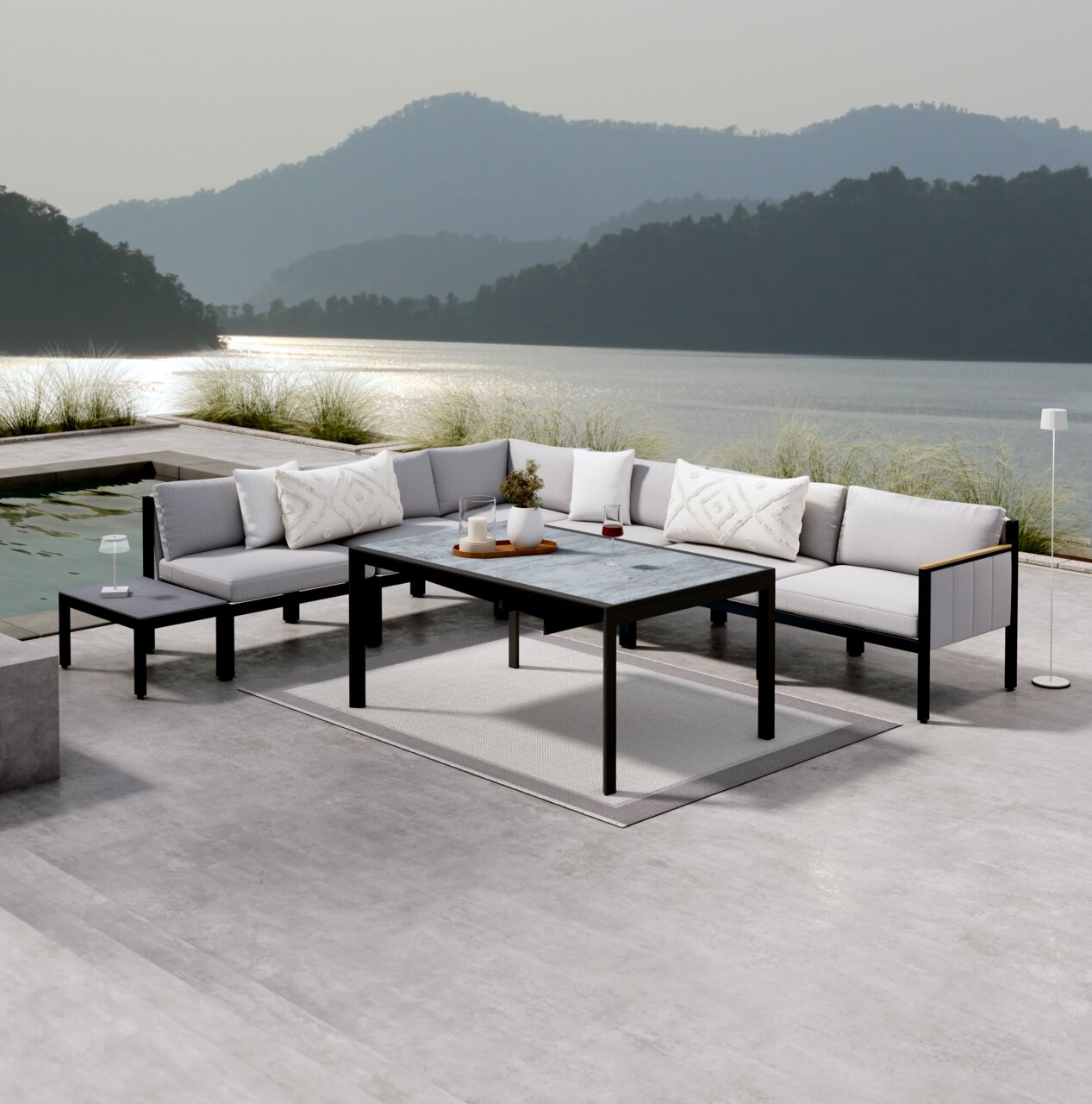Dieter Knoll Lounge-Sofa Armteil rechts ABEL Moderne Lounge-Möbel auf einer Terrasse mit Seeblick, bestehend aus einem Ecksofa, einem Gartentisch und einem Beistelltisch, von vorne betrachtet.